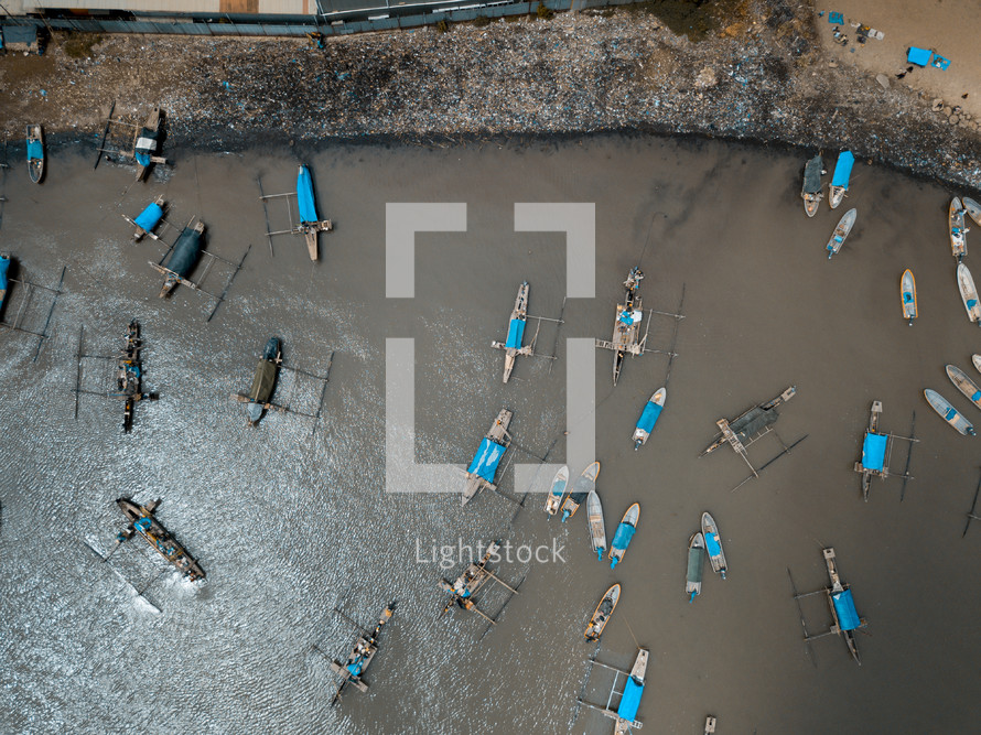 aerial view over boats in a muddy bay 