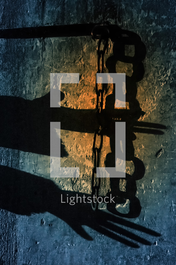 Shadow of a prisoner's hands with chains on a grungy colorful wall. Slavery concept
