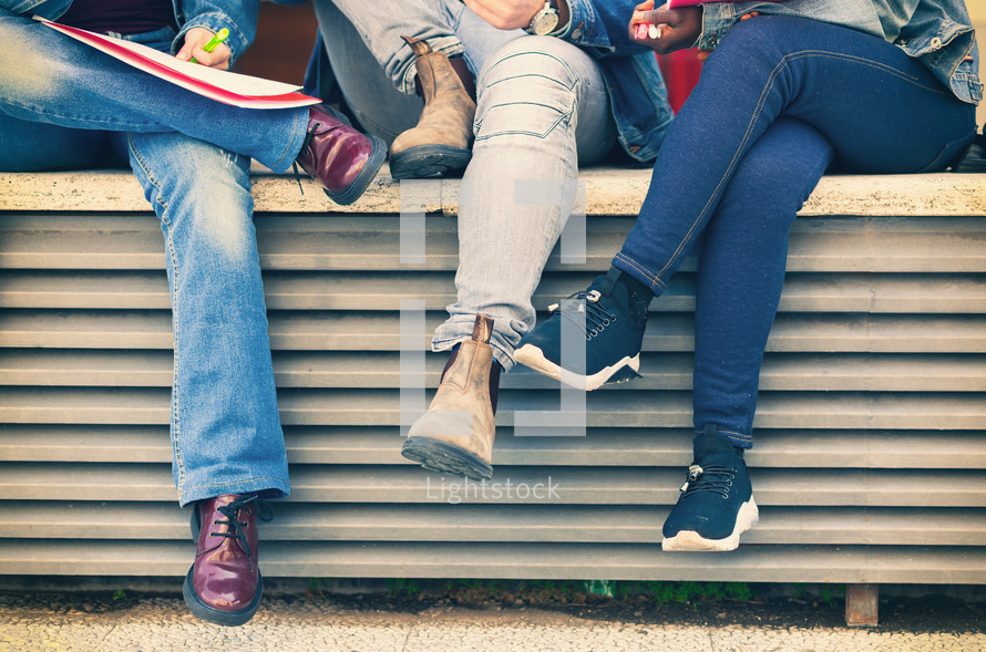Legs of students sitting on a bench. Study concept.