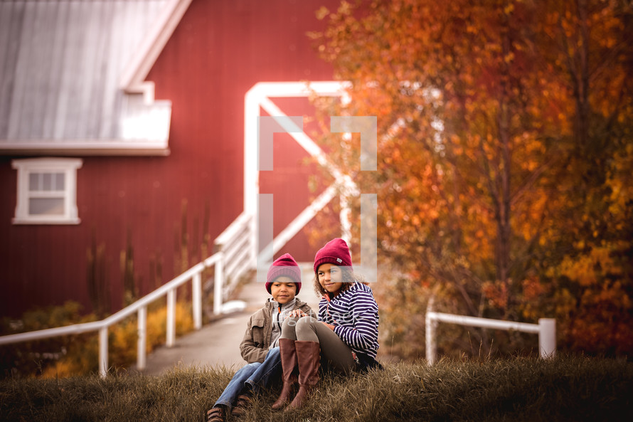 children sitting near a barn 