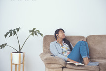 a girl sitting on a couch listening to an Audio Bible 