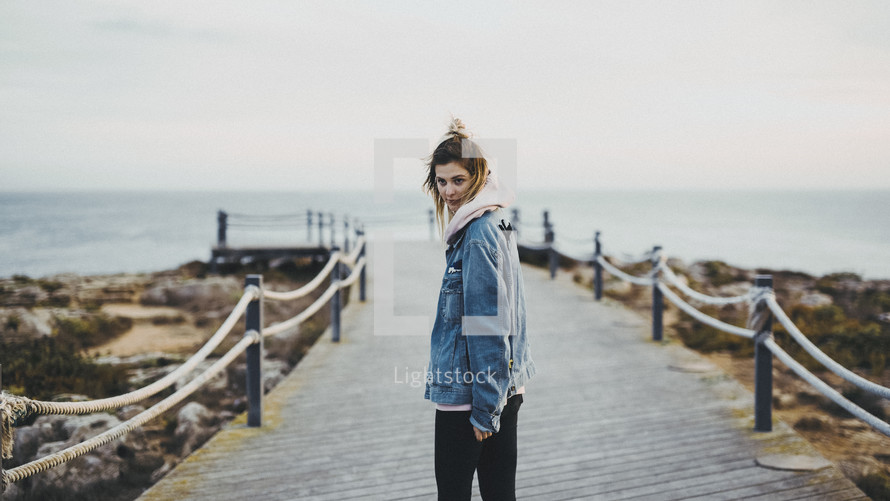 woman walking down a pier and looking back at the camera 