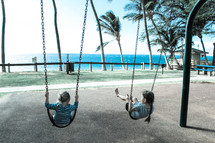 girls on swings by a beach 