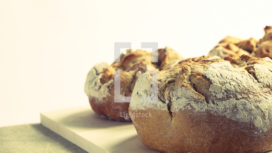 Three fresh loaves of bread on a cutting board