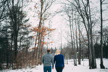 couple walking holding hands in snow 
