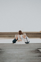 siblings sitting on a dock 
