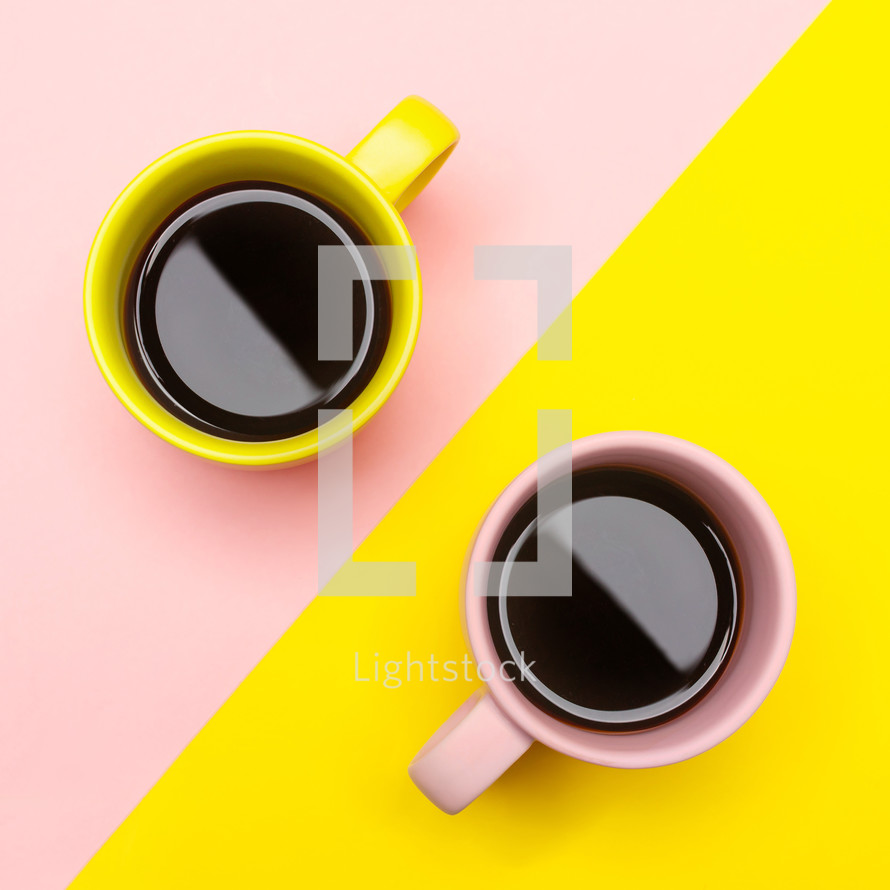 Flat lay top view of a two coffee cups with pink and yellow