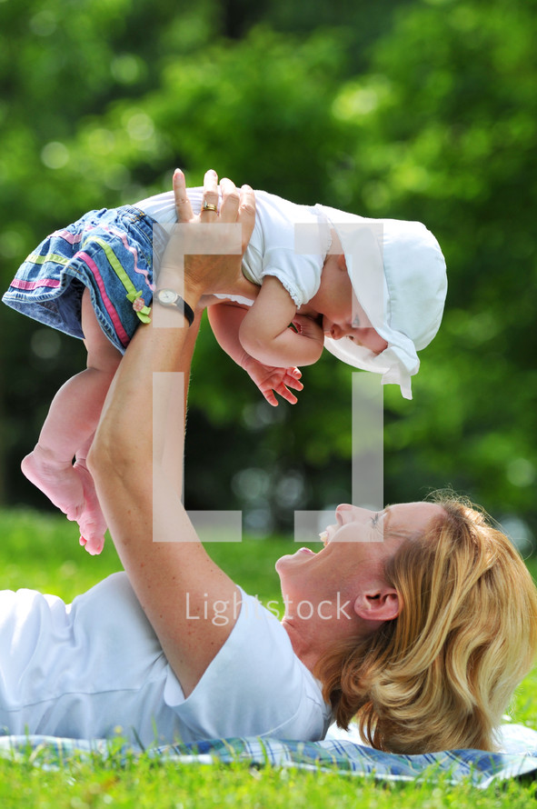 mother holding her infant daughter in the air 