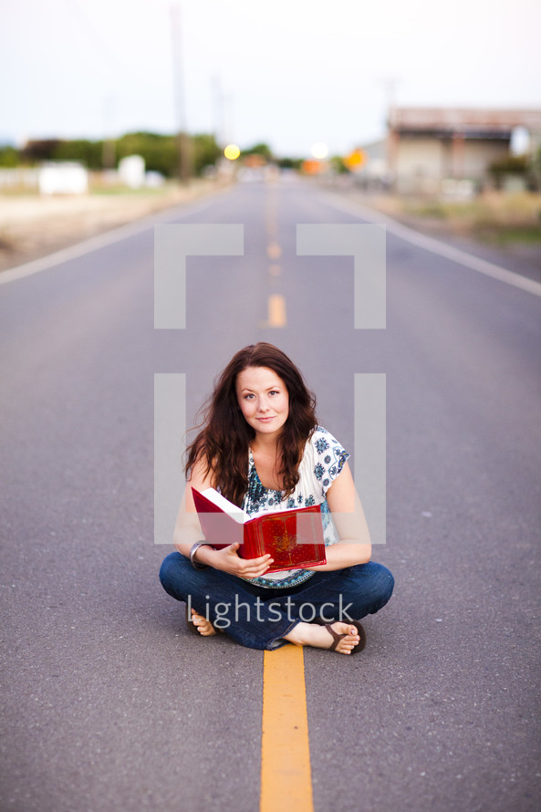 woman sitting in the middle of the street reading bible