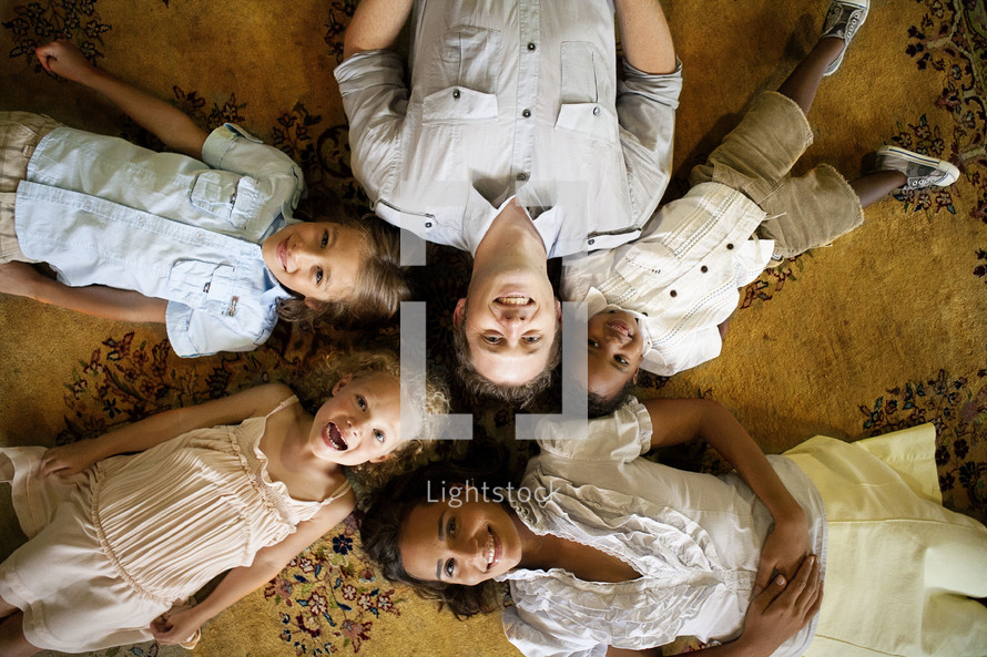 man and four children lying on floor - heads together