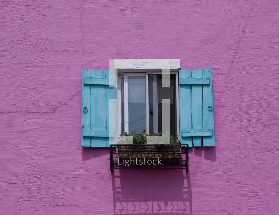 Blue and white window with flower box on bright pink wall