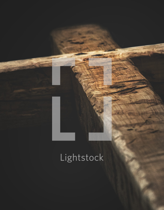 Light shining on a heavy wooden cross.