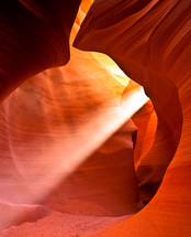rays of sunlight shining in a red rock cave 