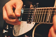Man's hands strumming guitar.