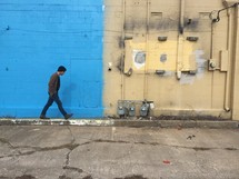 man walking down a sidewalk behind stores 