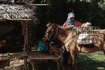 a man loading a basket over the side of a horse 