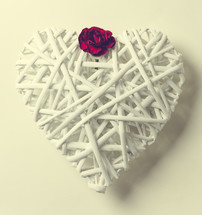 A white heart made of twigs with a red flower.