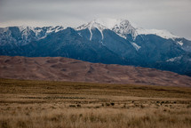 snow capped mountain peaks and sand dunes 