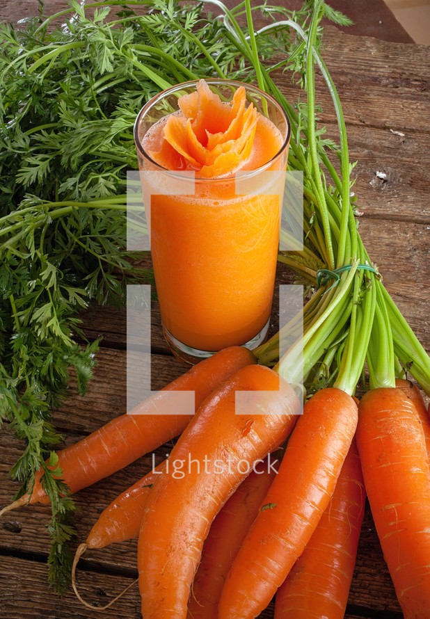 Fresh carrot juice glass with fresh organic carrots on wooden table