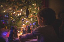 boys playing with a nativity scene under a Christmas tree