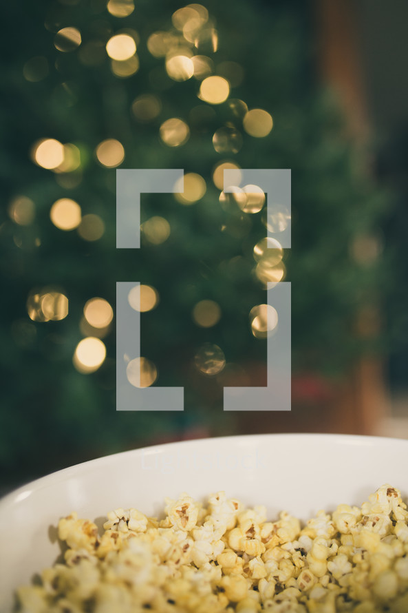 bowl of popcorn in front of a Christmas tree 