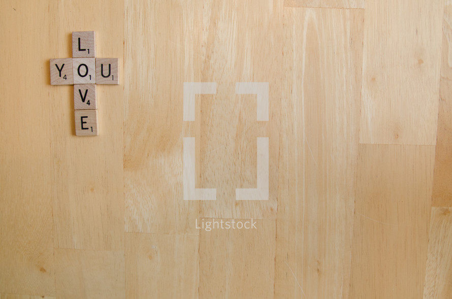 Scrabble letters arranged in form of cross saying "Love you".