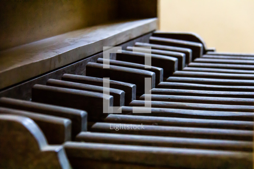 The wooden pedalboard of a vintage pipe organ in profile