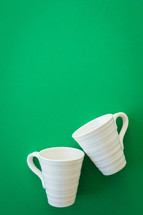 white coffee mugs on a green background 