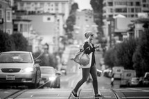 a woman with a purse crossing a busy street 