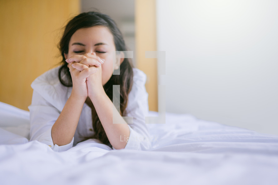 a girl praying at her bedside 