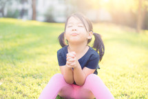 toddler girl with praying hands outdoors 