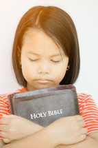 a girl hugging a Bible 