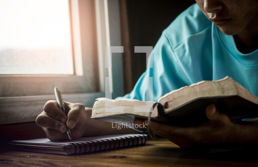 a man reading a Bible and taking notes