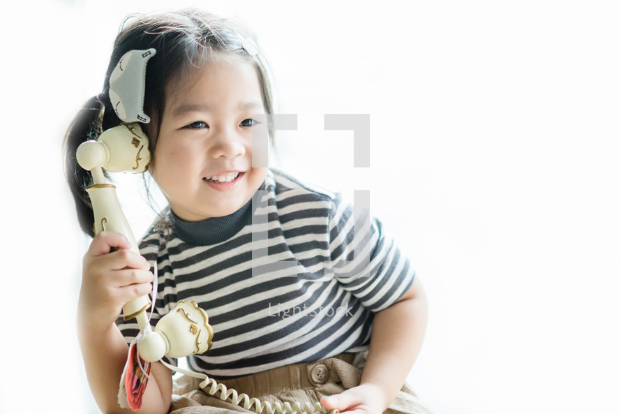 a toddler girl on an antique phone 