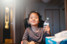 a little girl drinking a bottle of water 