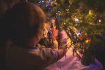 boys playing with a nativity scene under a Christmas tree