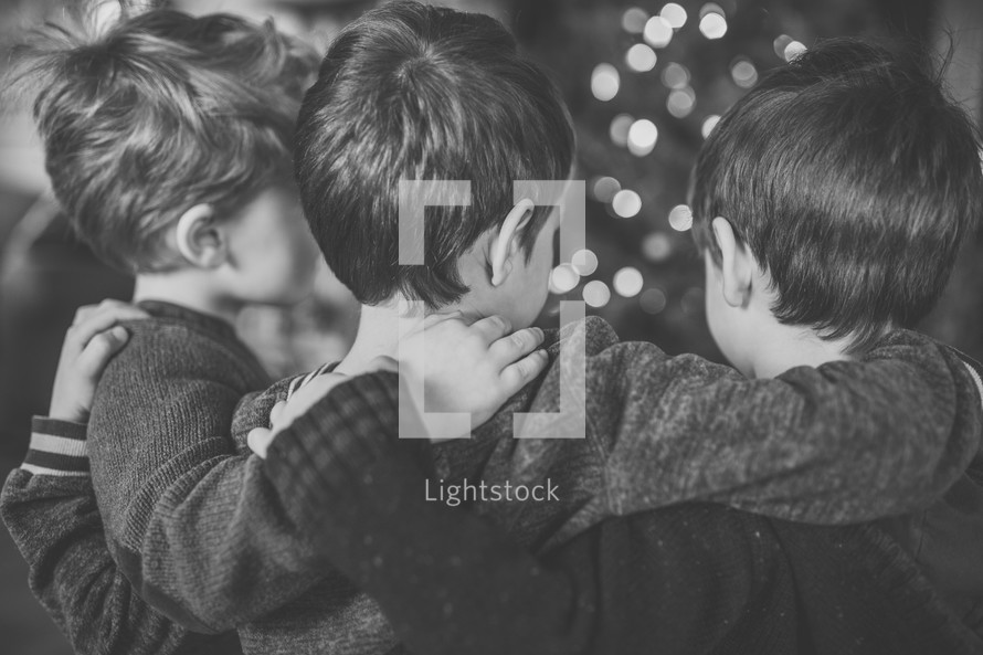 brothers hugging in front of a Christmas tree 