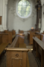 Oval, ornate window over a pew