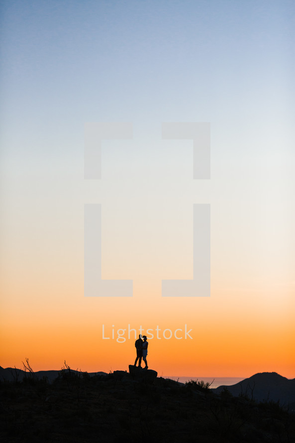 silhouette of a couple against an orange sky 