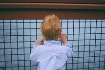 red headed little boy looking out at the water 
