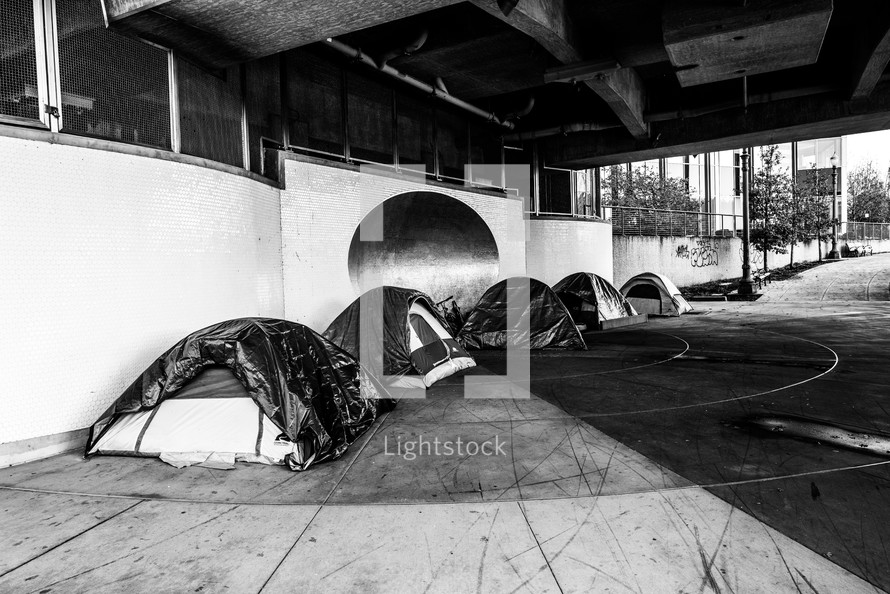 homeless sleeping in tents under an overpass 