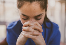 A young woman with hands folded in prayer