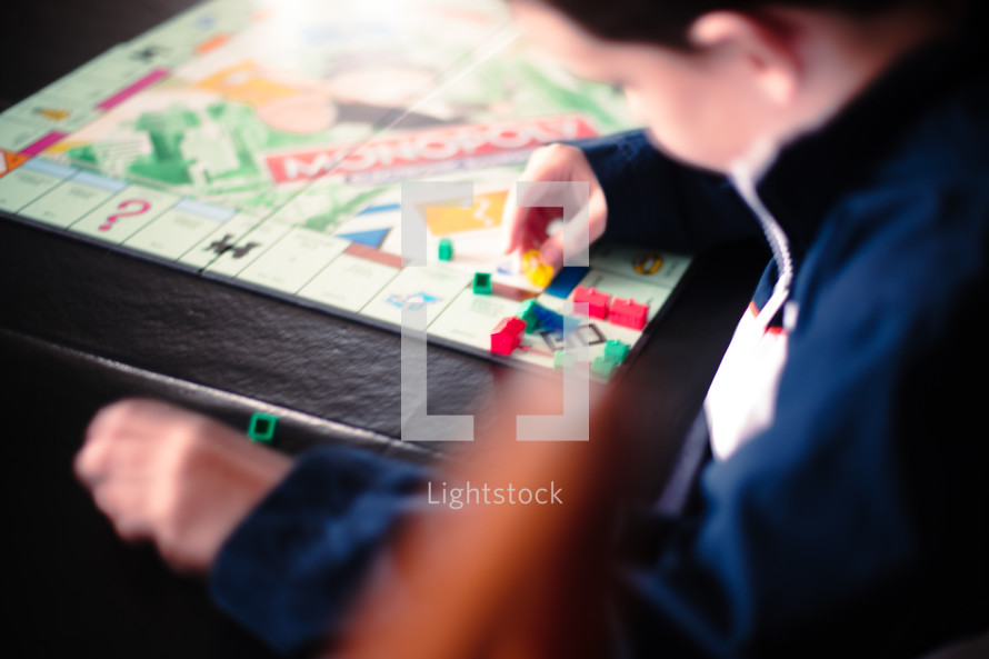 A boy plays with game pieces on a board game.