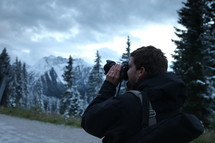 man taking a picture of mountains with his camera 