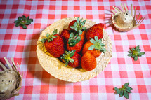 Fresh strawberries decorated on a straw hat. on a red picnic blanket.