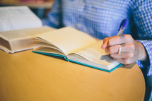 Person studying the bible making notes in a notebook