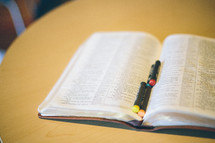 Open bible on a table with pastel chalks laying in it