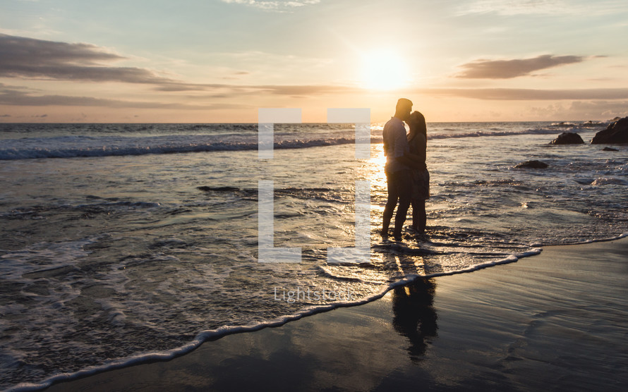 a couple embracing on a beach at sunset 