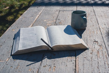 A Bible with a cup of coffee on a rustic back porch,.