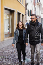 couple walking holding hands on a cobble stone street 